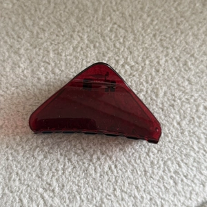 Detailed top view of a triangular burgundy translucent hair claw clip on textured fabric