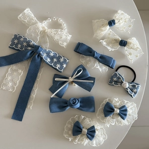 Detail of French style lace and denim hair accessories with pearls on white surface