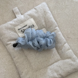 Detailed close-up of light blue chiffon fabric ruffles on a sleek banana hair clip