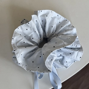 Detailed view of light blue polka dot scrunchie with a soft ribbon bow decoration