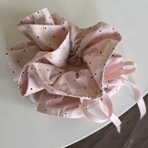Pink polka dot hair scrunchie with satin ribbon detail on a white surface