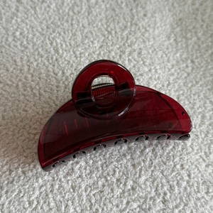 Close-up of translucent burgundy hair claw clip made of acrylic on a white textured background