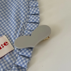 Nahaufnahme einer mattgrauen herzförmigen Acryl-Haarklammer mit goldenem Entenschnabelclip