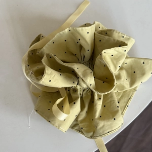 Close-up of yellow polka dot fabric drawstring pouch with soft satin ribbons