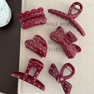 Close-up of assorted burgundy polka dot hair claws in various geometric shapes