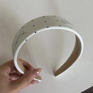 Detail of white satin headband with black polka dots and embroidered bow decoration