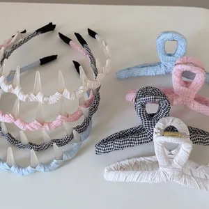 Détail de divers serre-têtes et grandes pinces à cheveux en tissu à carreaux bleu et rose