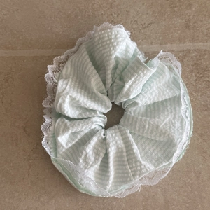 Détail d'un chouchou vert menthe rayé avec bordures en dentelle blanche et coton doux