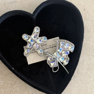 Sparkling rhinestone star and butterfly hair clips set on a black velvet heart cushion