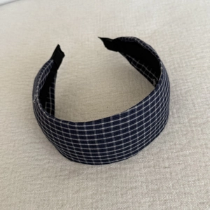 Vue détaillée du serre-tête large à carreaux bleus montrant la texture et le design