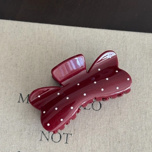 Close-up of red hair claw clip with white polka dots and irregular bow shape