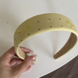 Detail of yellow polka dot wide headband with elegant bow embroidery craftsmanship
