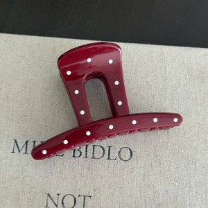 Close-up of a dark red French style hair claw clip with white polka dots on fabric