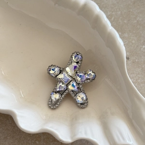 Detailed close-up of rhinestone starfish hair clip on a white shell porcelain tray