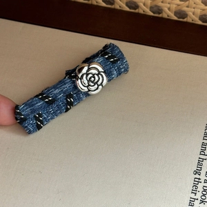 Detailed close-up of blue denim fabric hair clip with a silver metal camellia flower