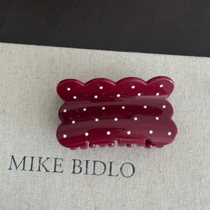 Detailed view of dark red wavy hair claw clip with white polka dots and glossy finish