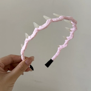 Serre-tête à carreaux roses avec des pointes 3D blanches tenu à la main