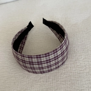 Gros plan d'un bandeau large à carreaux violet-brun avec doublure en tissu noir confortable