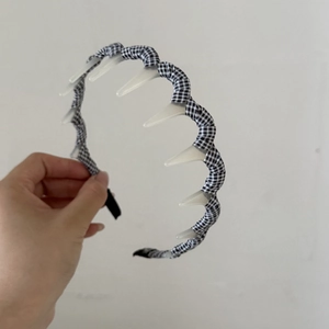 Détail d'un serre-tête vichy noir et blanc avec dents intérieures pour fixer la coiffure