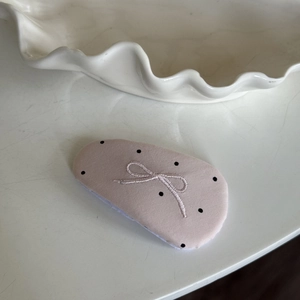 Detail of light pink polka dot fabric hair clip with a silver embroidered bow decoration
