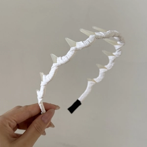 Détail du serre-tête en tissu à rayures blanches avec des éléments décoratifs pointus