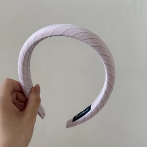 Gros plan du serre-tête plissé rose montrant l'étiquette faite main et la texture du tissu