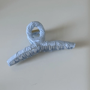 Détail d'une pince à cheveux à carreaux bleu clair avec ressort en métal doré