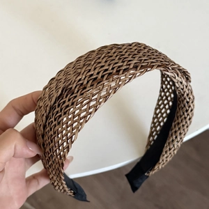 Detail of woven straw headband featuring intricate caramel braided texture and mesh design
