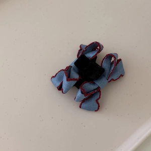 Blue denim bow hair claw with red wavy stitching and a small black clip for styling