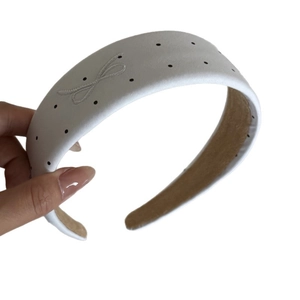 Grey fabric headband with black polka dots and embroidered bow on white background