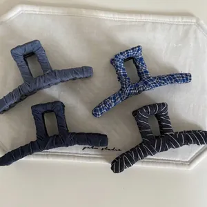 Detailed view of four retro fabric-wrapped square claw clips in assorted denim and stripe patterns