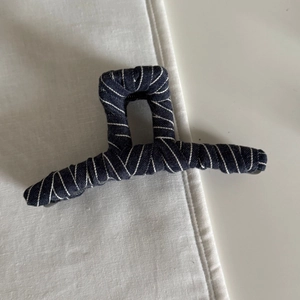 Vintage navy denim fabric claw clip with white diagonal stitching on white surface