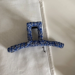 Top view of blue and white plaid fabric hair claw clip with internal metal spring