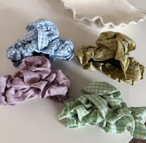 Set of four plaid fabric claw clips in pastel colors with ruffled edges on white tray