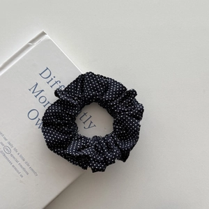 Polka dot denim scrunchie for ponytails placed on a book in a minimalist setting