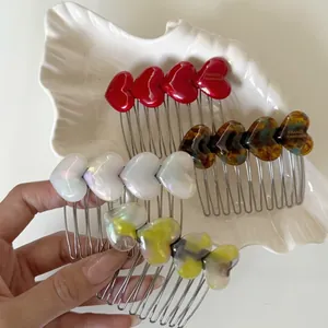 Macro shot of acetic acid heart hair combs in four colors on a white ceramic tray