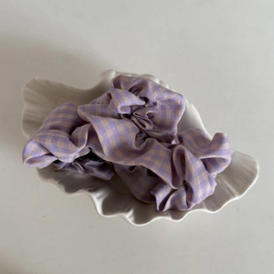 Close-up of purple gingham fabric hair scrunchies displayed in a shell-shaped tray