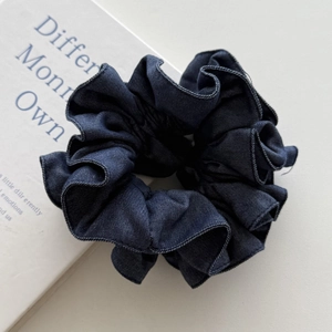 Detailed macro view of dark blue denim hair scrunchie with white contrast stitching edge