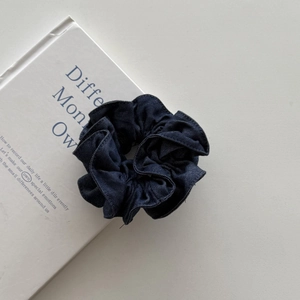 Macro shot of deep blue denim fabric texture and stitching on a scrunchie
