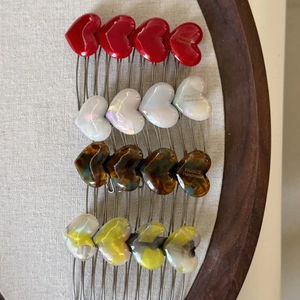 Handmade heart-shaped acetate hair combs in red, pearl, and tortoiseshell patterns