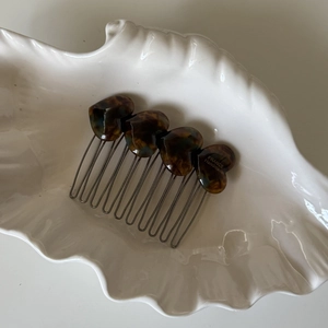 Elegant acetate heart hair comb with tortoiseshell pattern on a decorative shell tray