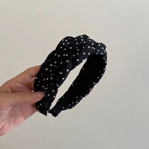 Detailed view of black headband with white polka dots and elegant pleated fabric texture