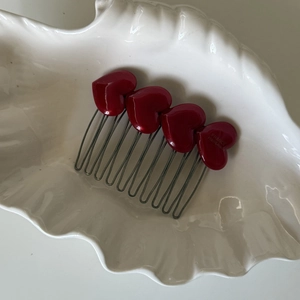 Detailed view of handmade acetate heart hair comb with red resin charms and metal teeth