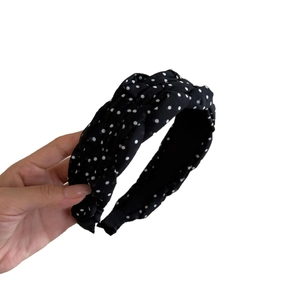 French style polka dot headband in black fabric with twist knot design held by hand