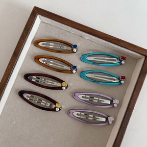 Detail view of colorful acrylic hair clips with faux pearls and gems in a wooden tray
