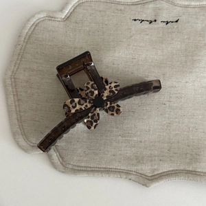 Macro shot of large dark brown leopard print flower hair claw clip on linen cloth