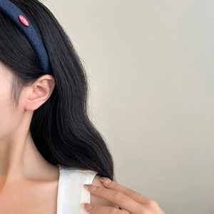 Minimalist denim blue headband with red letter label worn by model on light background
