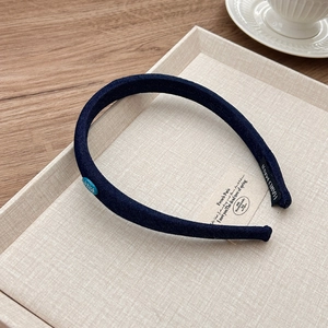 Detail view of denim headband with red label and handcrafted stitch on woven tray