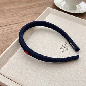 Detail view of denim headband featuring red button accent and hand made woven label detail