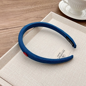 Detailed texture of blue denim headband with red logo label and handmade inner tag